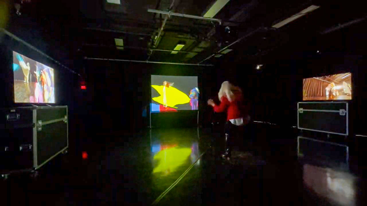 Une femme danse devant une projection colorée.