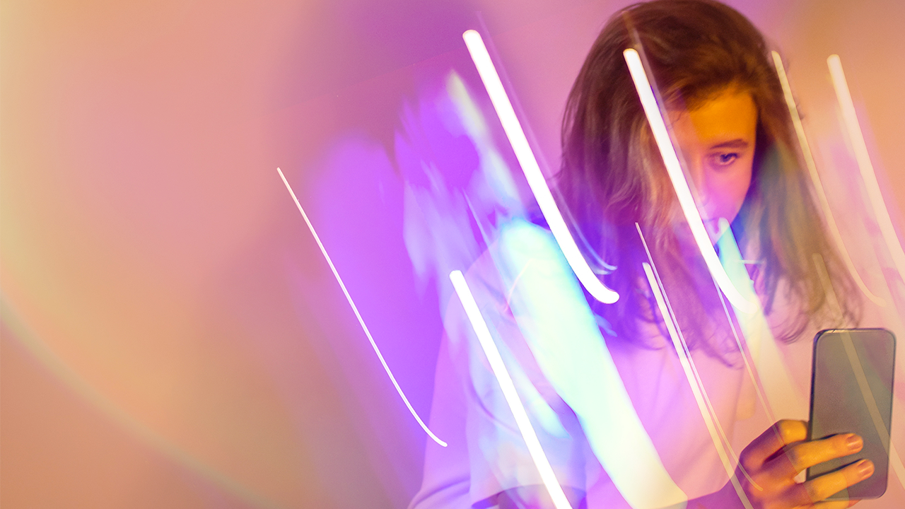 Une femme dans des traits lumineux tiens un téléphone cellulaire